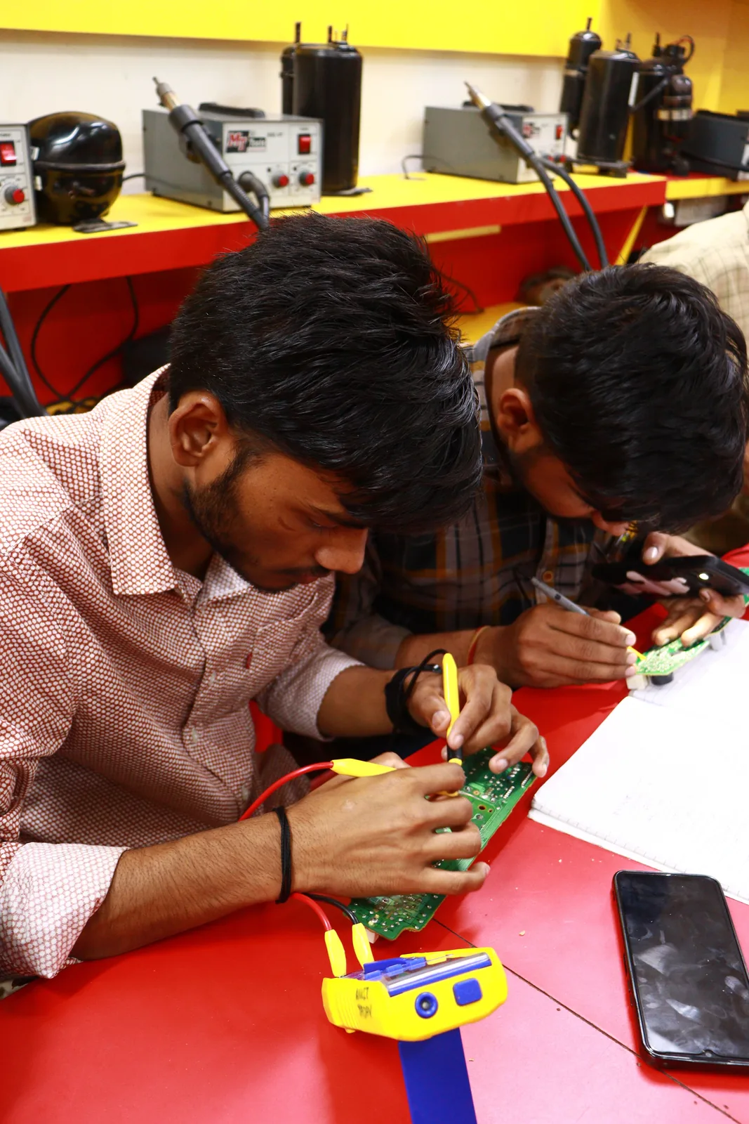 Students learning circuit-board repair in a workshop